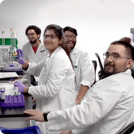 Four scientists working at a lab smiling at the camera